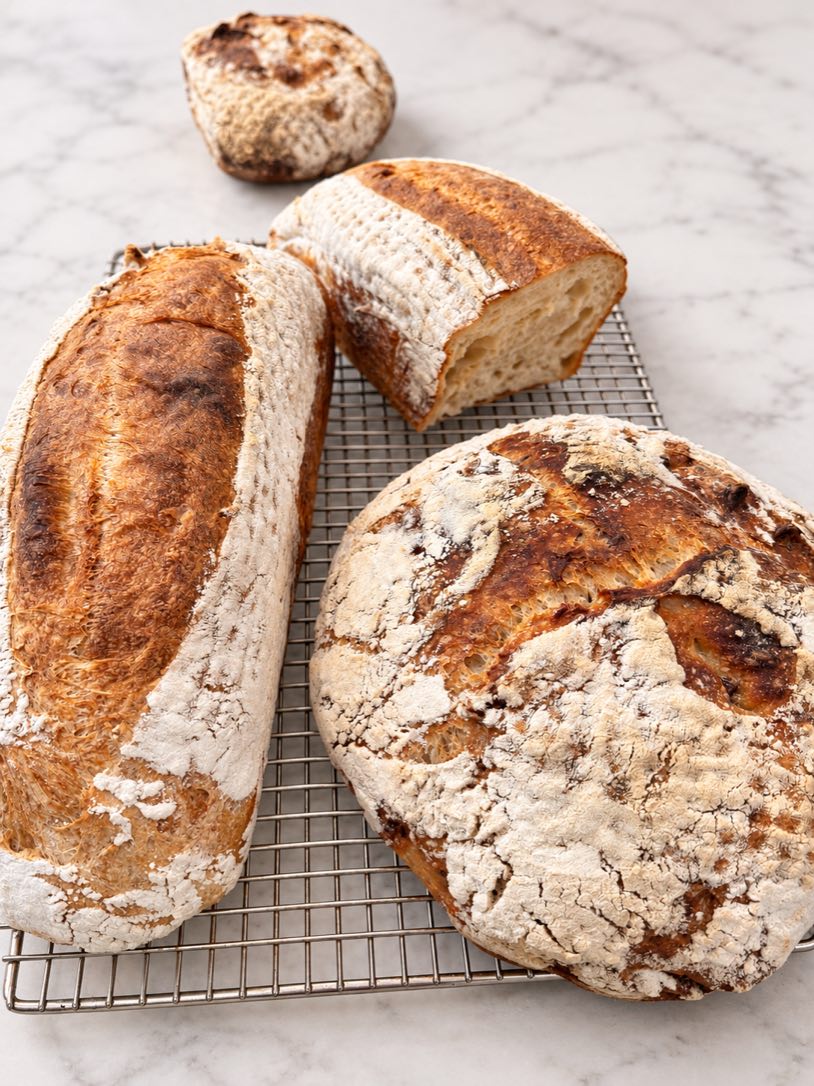 Country Blonde with Pecan and Double-Fed Sweet Levain loaves cooling on a wire rack.